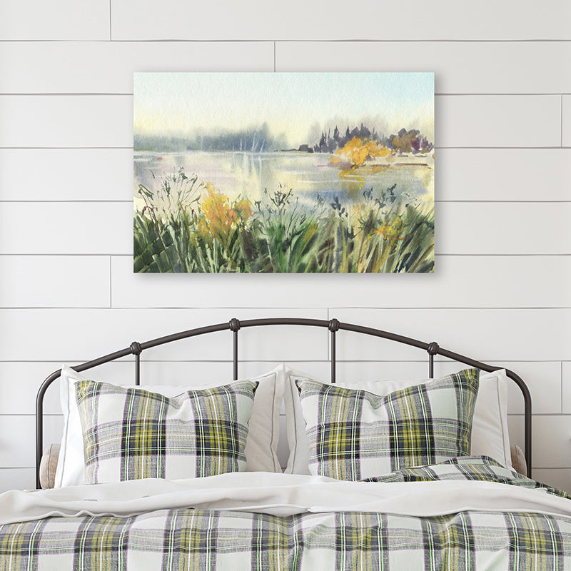 Art print of a watercolour landscape artwork in green, gold and soft grey displayed in a country-style bedroom.