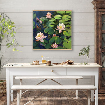 Canvas art print of green lily pads and pink lilies floating on dark pond water displayed behind a rustic farmhouse dining table.