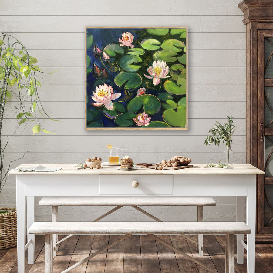 Canvas art print of green lily pads and pink lilies floating on dark pond water displayed behind a rustic farmhouse dining table.